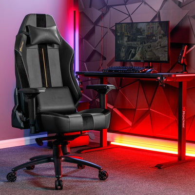 Gaming chair in a room with red and purple lighting, featuring a desk with a computer setup.